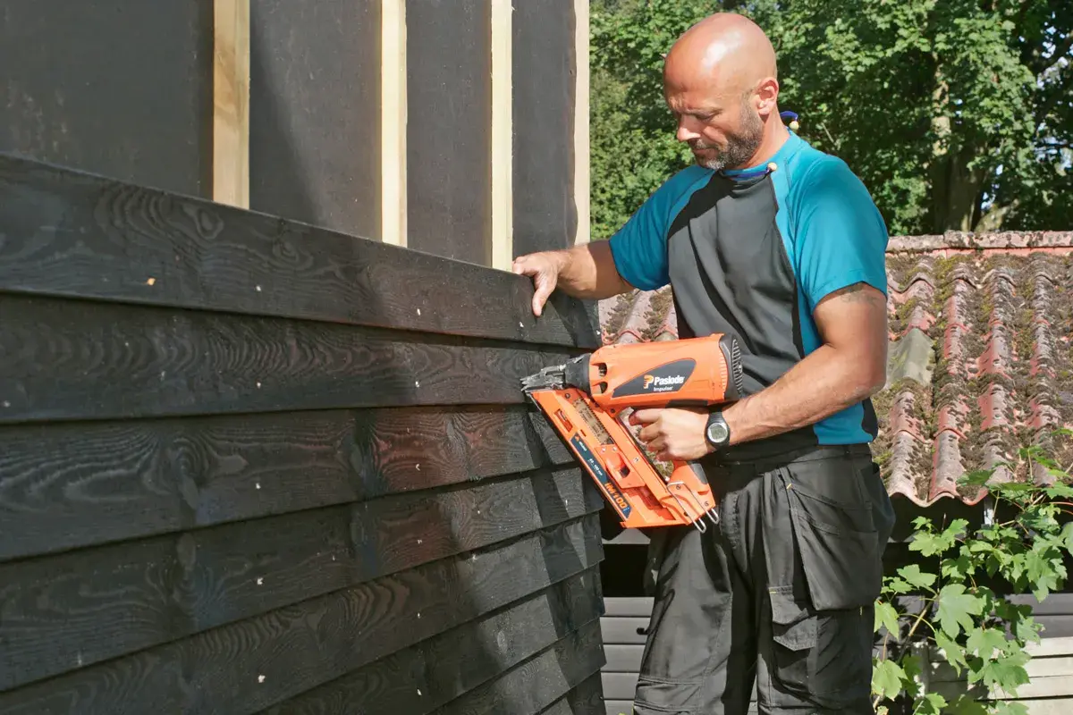 Man monterar liggande panel med spikpistol.