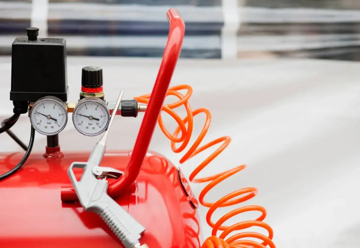 Detalles de un compresor de aire rojo con manómetros y pistola. Aprende como limpiar un compresor de aire para un óptimo funcionamiento.