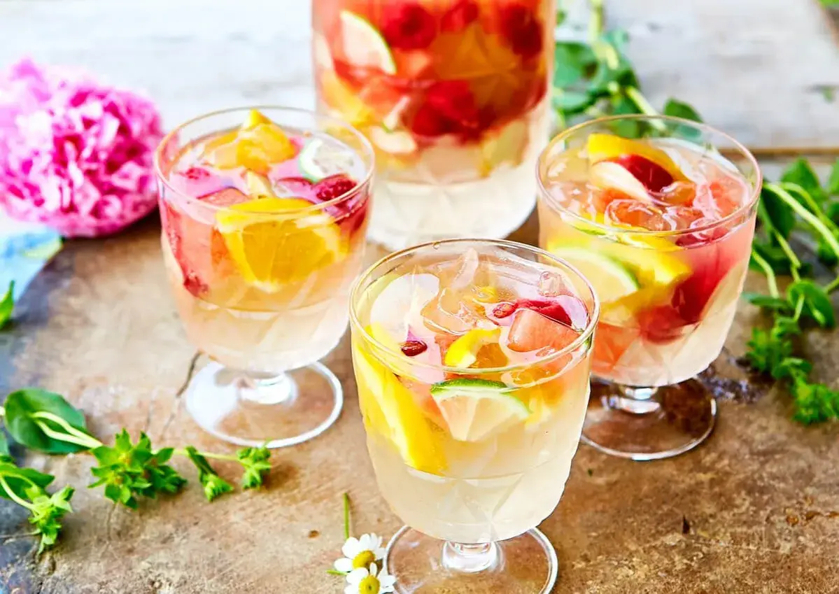 Tre glas med uppfriskande sangria vit fyllda med frukt och is. En perfekt sommardrink!