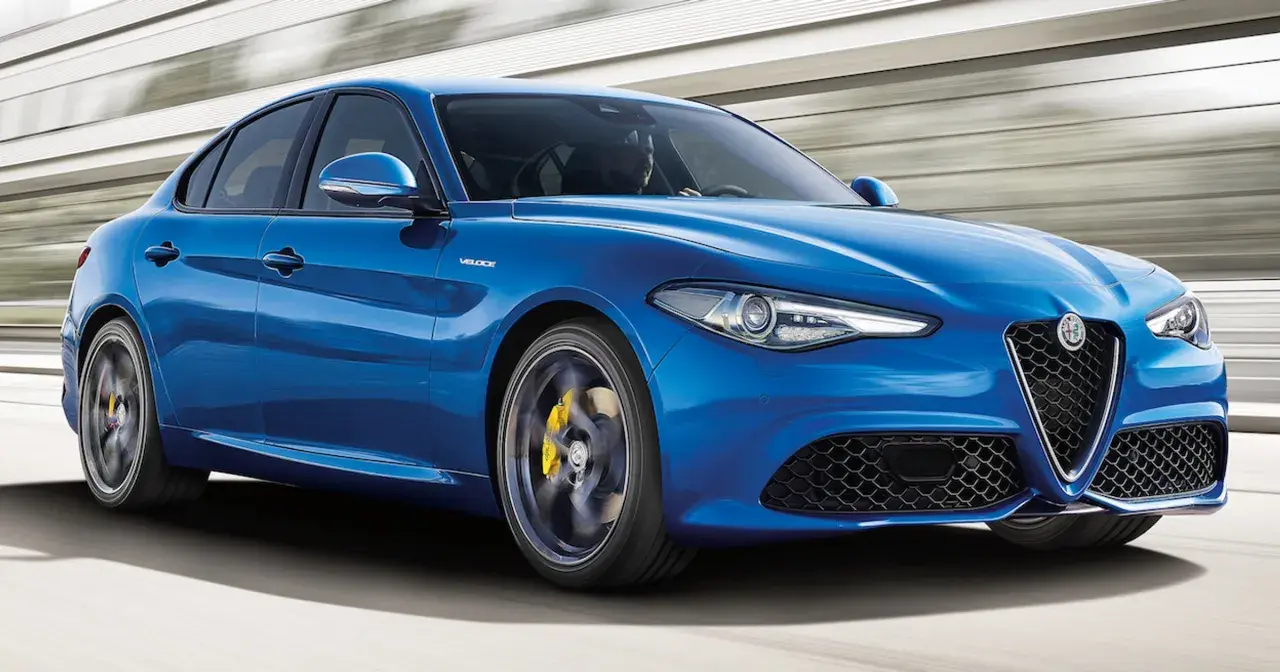 Błękitne Alfa Romeo Giulia Q4 Veloce w ruchu, z żółtymi zaciskami hamulcowymi i sportowym wyglądem.