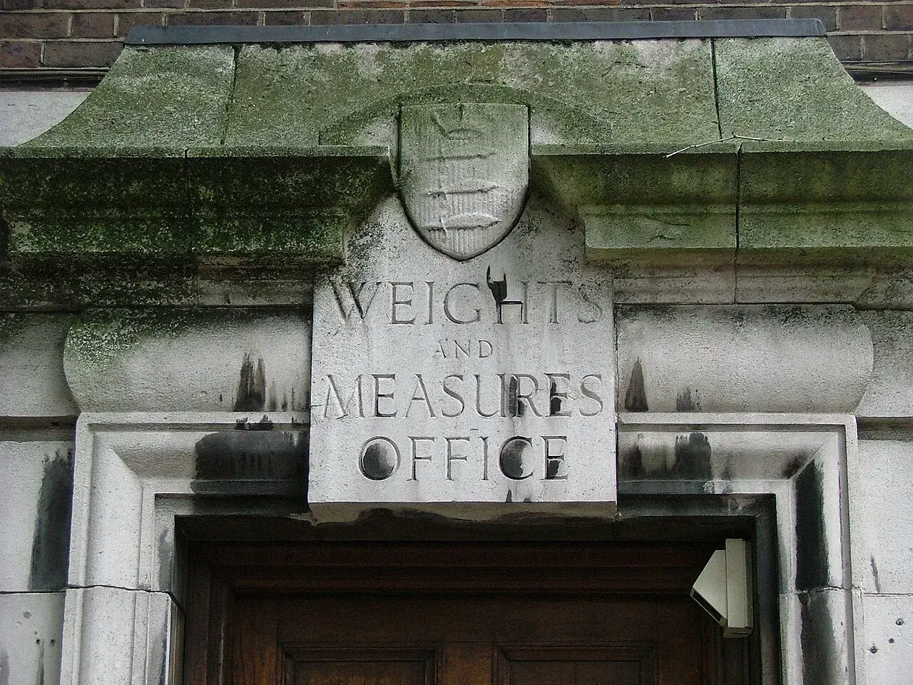 Napis "Weights and Measures Office" nad drzwiami, symbolizuje miarę długości w Anglii.