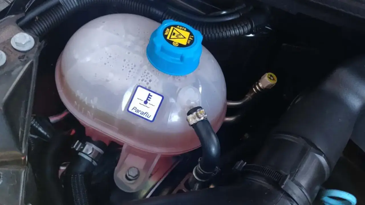 Depósito de expansión del refrigerante de un coche. El símbolo de termómetro y "Paraflu" indican el líquido anticongelante.