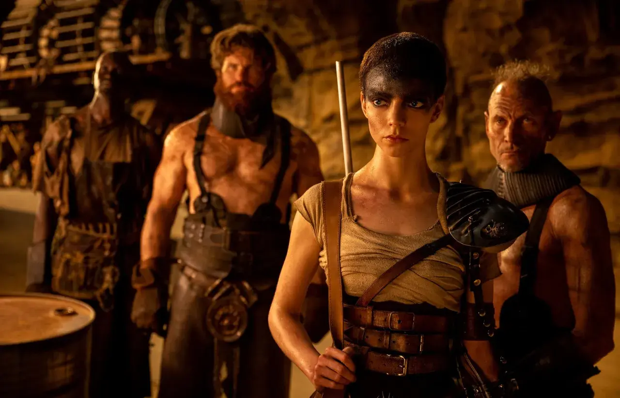 Furiosa z "Sagi Mad Max" w otoczeniu groźnych towarzyszy, gotowa do walki w postapokaliptycznym świecie.