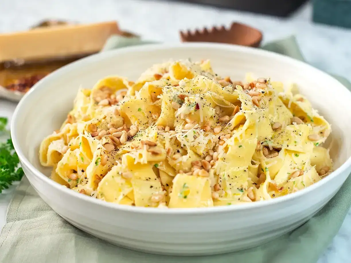 En skål med krämig citronpasta, toppad med pinjenötter och riven parmesan. En härlig rätt som passar perfekt för en snabb och smakrik middag.