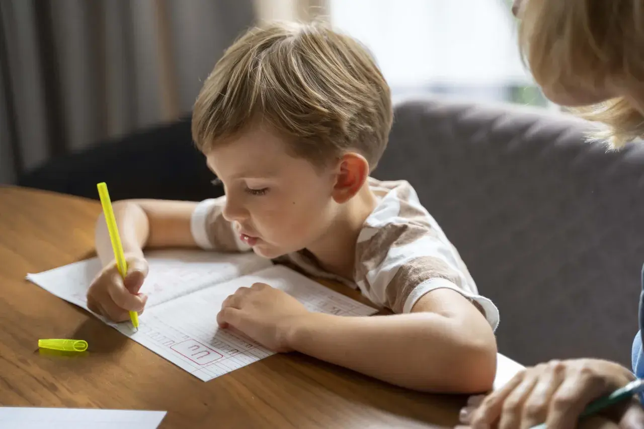 Niño concentrado practicando caligrafía en un cuaderno, un paso clave para como mejorar la letra de un niño.