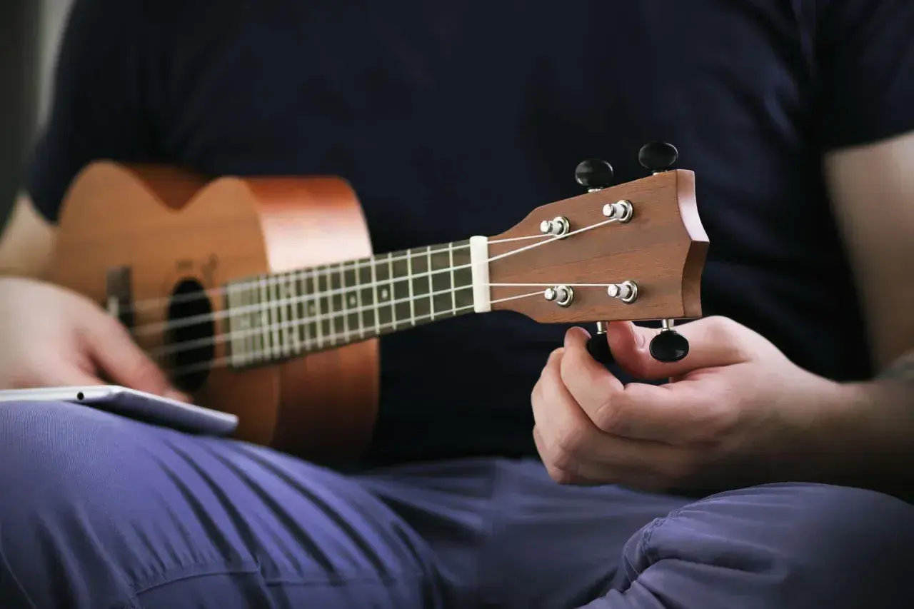 Dłoń kręci kluczem, strojenie ukulele przed graniem.