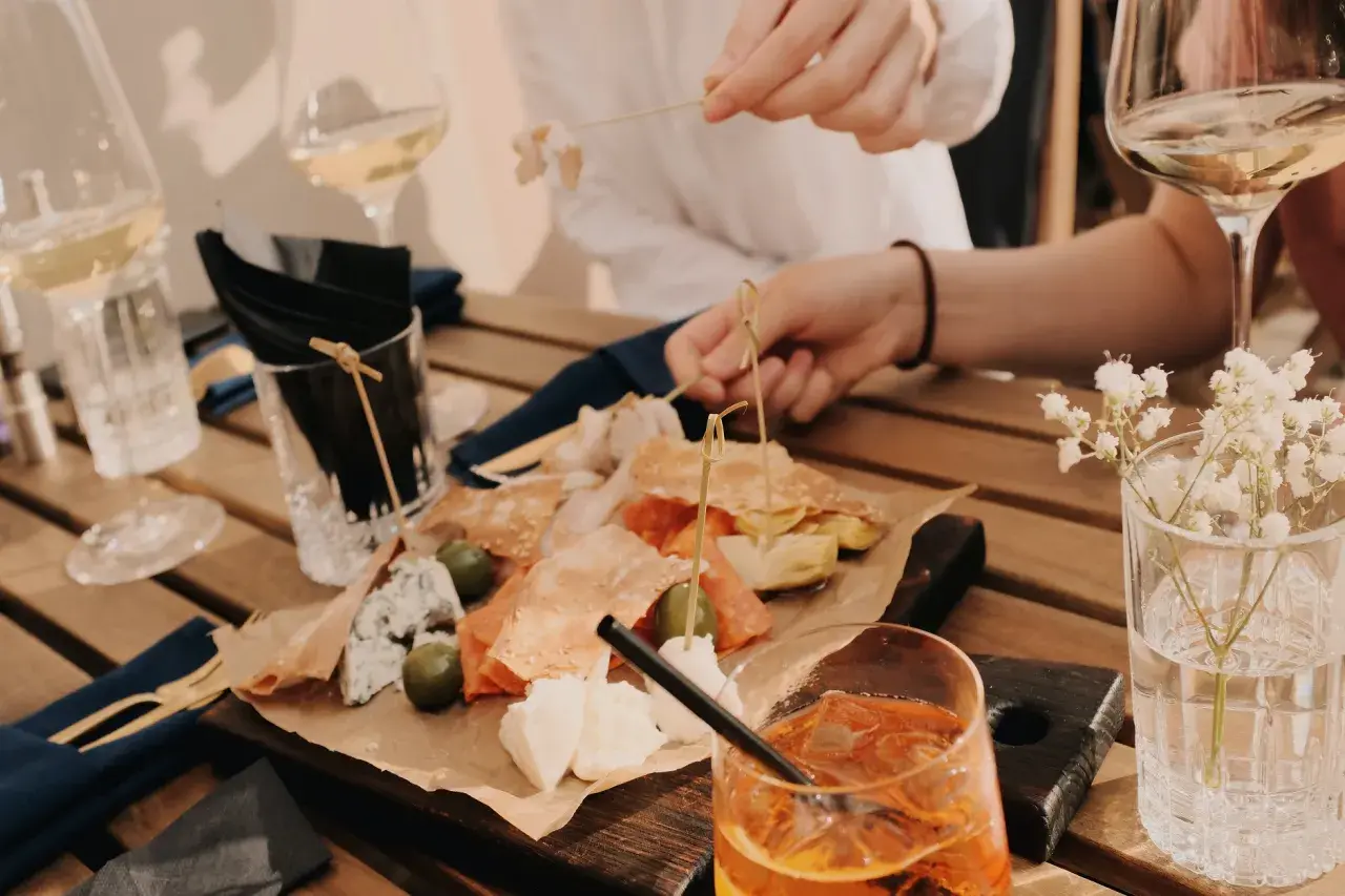 Leckereien auf einer Holzplatte, wie auf einer food pairing tabelle. Dazu Weißwein und ein Aperol Spritz.