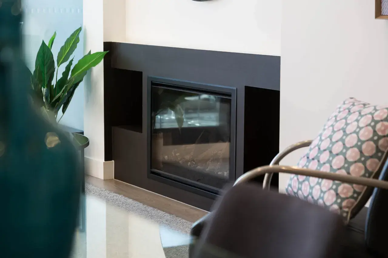Moderner Kamin mit Glasfront und dekorativer Pflanze. Regelmäßiges Kehren ist wichtig, um die Sicherheit zu gewährleisten.