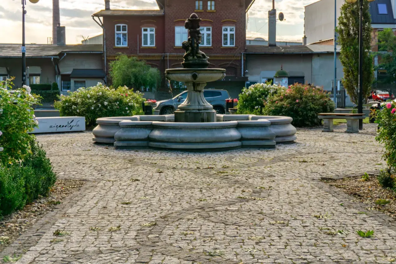 Kamienna fontanna i ławka w otoczeniu kwitnących krzewów róż tworzą urokliwy zakątek, jakby z najładniejszej wsi w Polsce.