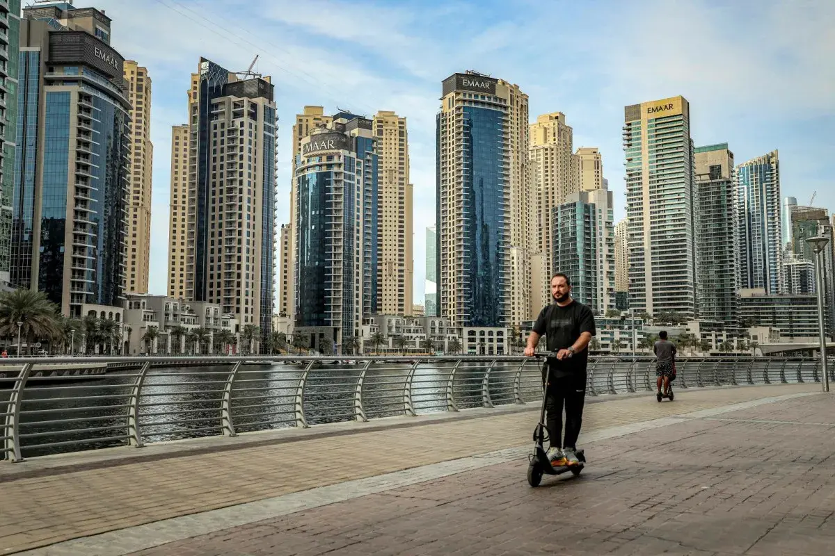 Mężczyzna na hulajnodze w Dubaju, wśród drapaczy chmur. Czy to początek afery dubajskiej?