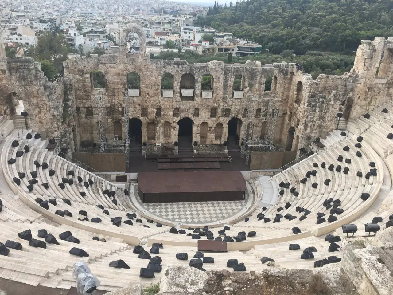 Starożytny Odeon Heroda Attyka w Atenach, z kamiennymi siedzeniami i sceną, w tle widać miasto.