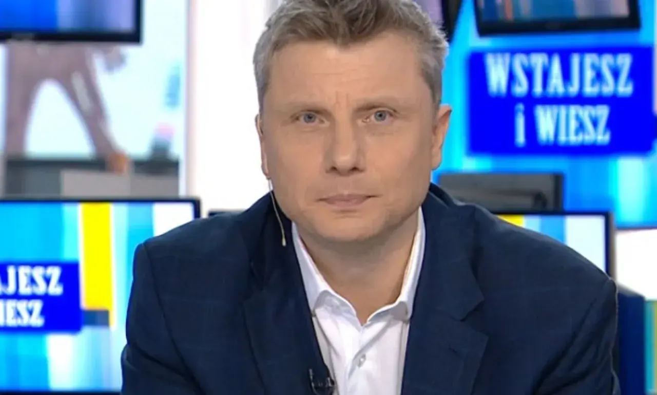 Rafał Wojda, wiek dziennikarza widoczny w jego spojrzeniu, w garniturze przed ekranem z napisem "Wstajesz i wiesz".