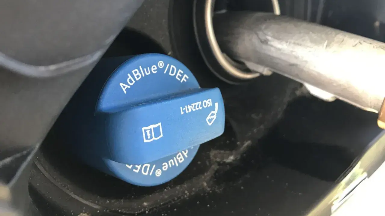 Niebieski korek wlewu AdBlue z napisem "AdBlue®/DEF" i symbolem ostrzegawczym. Sprawdź, ile adblue zostało.