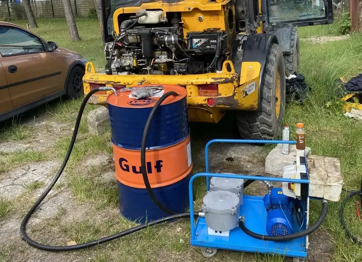 Wymiana oleju hydraulicznego w minikoparce. Beczka Gulf i pompa do płynów gotowe do pracy.