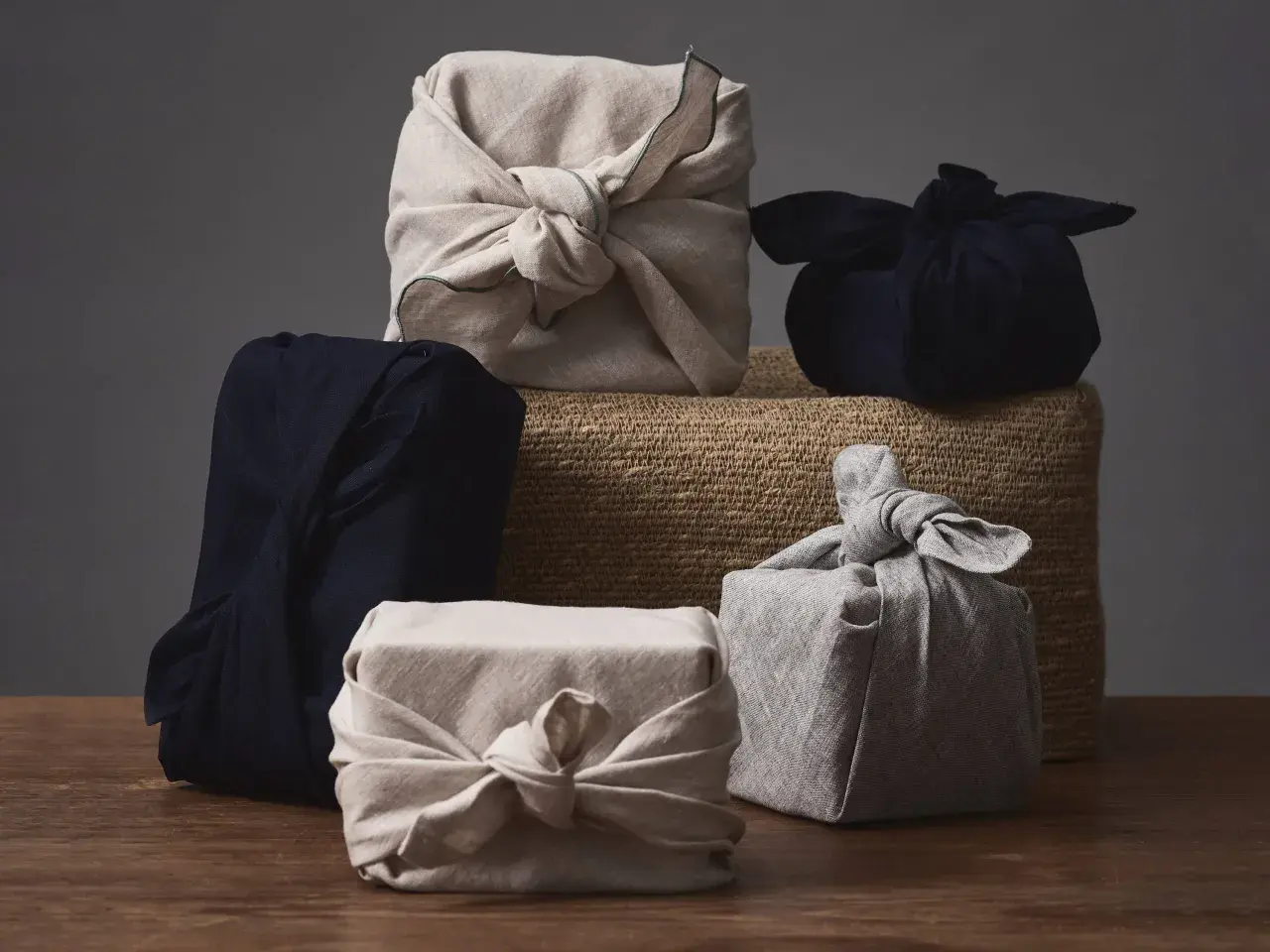Fünf Geschenke, in Stoff gewickelt und mit Stoffschleifen verziert, warten darauf, ausgepackt zu werden. Eine stilvolle Art, Kleidung zu verpacken, als Geschenk.