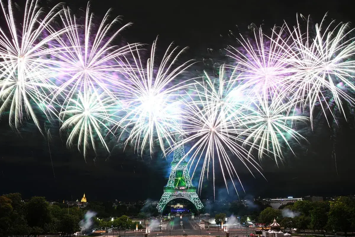 Spectaculaire feu d'artifice parisien illuminant la Tour Eiffel de mille feux. Des gerbes de lumière blanche et violette explosent dans le ciel nocturne.