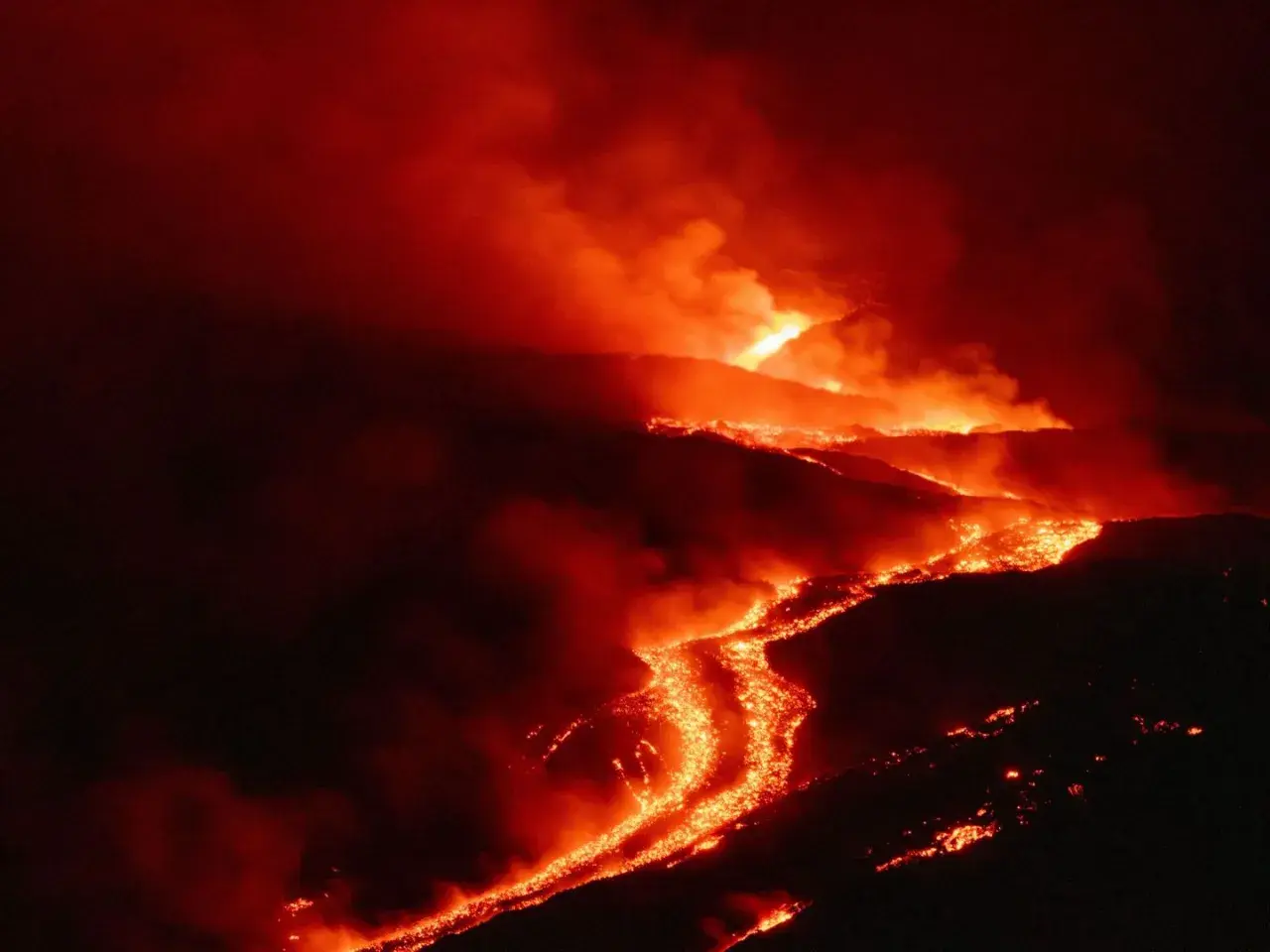 Glühende Lava fließt den Hang eines Vulkans auf Sizilien hinab, umgeben von Rauch und Dunkelheit.