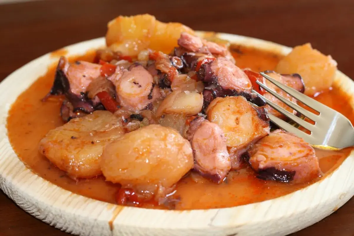 Pulpo a la mugardesa, un plato gallego con trozos de pulpo tierno y patatas cocidas en una salsa rojiza.