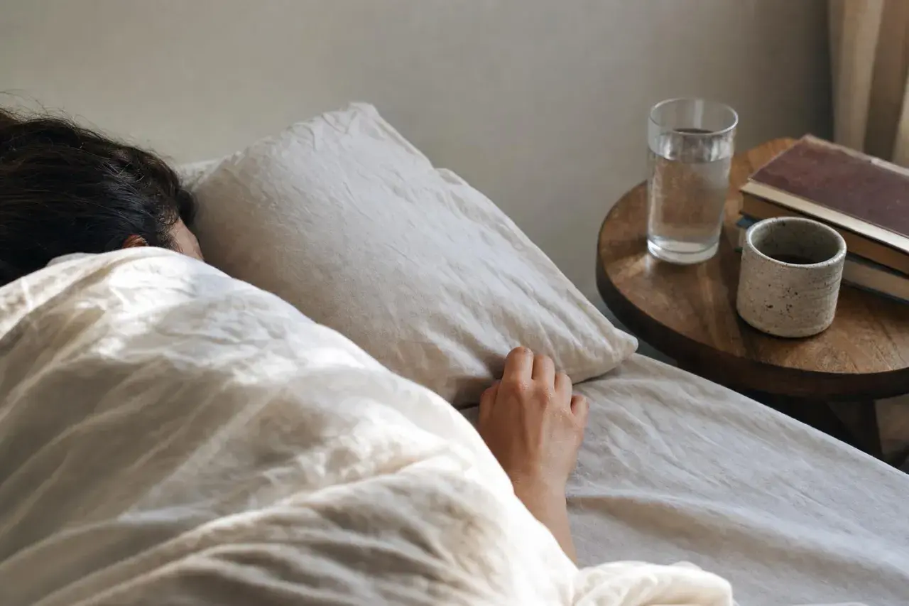 Una persona dorme avvolta nelle lenzuola, forse per sognare una vecchia fiamma. Sul comodino, un bicchiere d'acqua e dei libri.