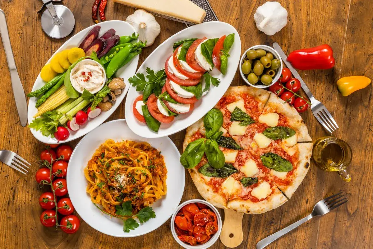 Italienische Pasta Vorspeisen: Tagliatelle Bolognese, Pizza Margherita, Caprese-Salat, Gemüsesticks mit Dip und Oliven. Ein Festmahl!