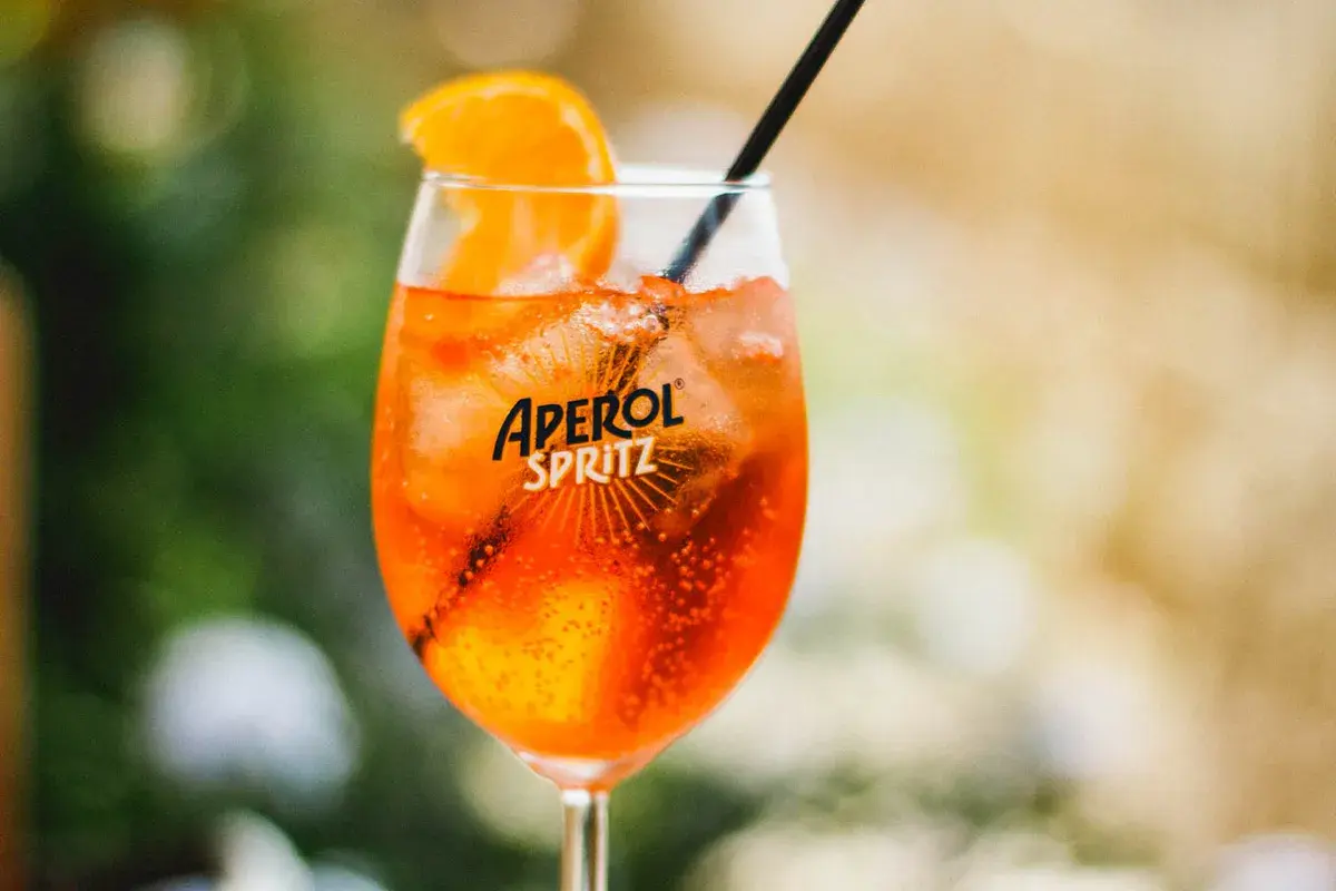 Ett glas med en orange Aperol Spritz, is och en apelsinskiva. Perfekt för en solig dag.
