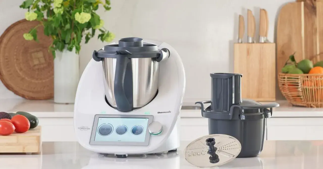 Biały Thermomix z ekranem dotykowym, akcesoriami i warzywami na blacie. Zastanawiasz się, ile wat ma Thermomix?