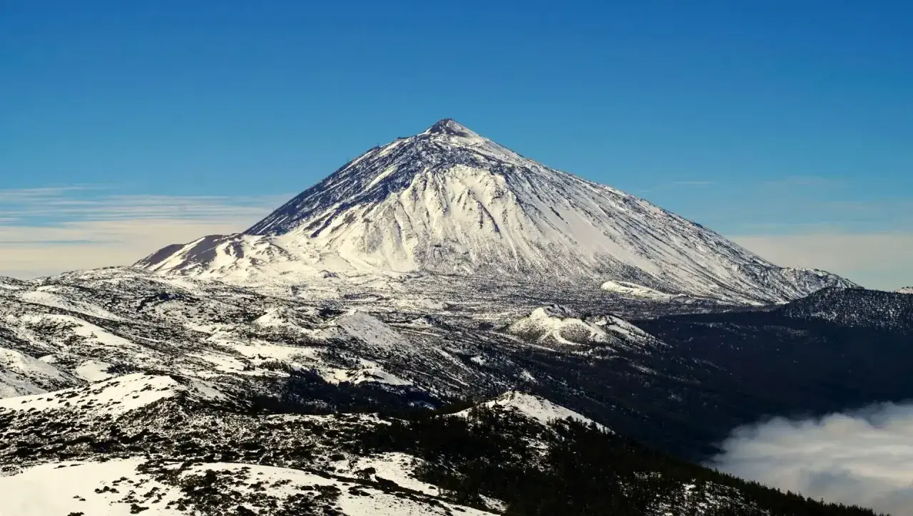 Schneebedeckter Teide-Vulkan auf Teneriffa im Dezember, ein beeindruckender Anblick über den Wolken.
