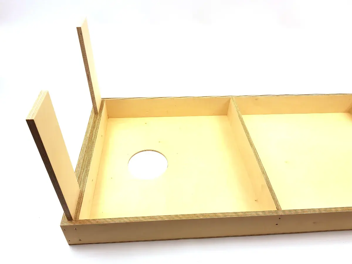 Holzplatte mit Loch für Cornhole selber bauen. Zwei aufgestellte Holzbeine deuten auf den Beginn des Projekts hin.