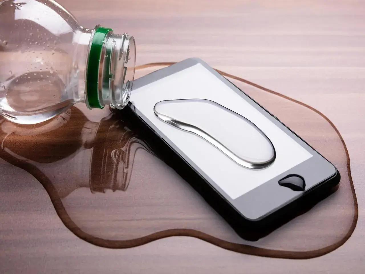 Telefon wpadł do wody, ale działa! Kropla wody na ekranie, a obok butelka.