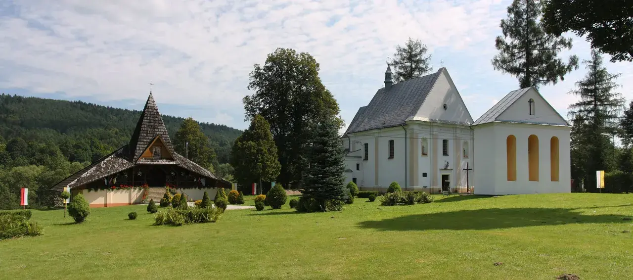 Ustrzyki Dolne atrakcje: drewniana cerkiew i biały kościół na tle zielonych wzgórz.