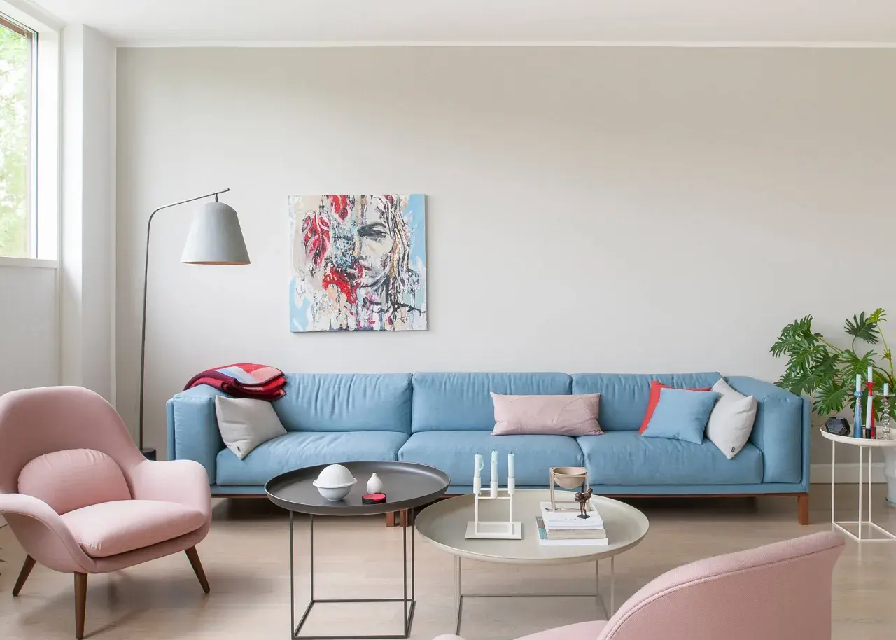 Ein hellblaues Sofa mit rosa Akzenten und einem abstrakten Gemälde. Welche Farbe passt zu altrosa? Hier wird es gezeigt.