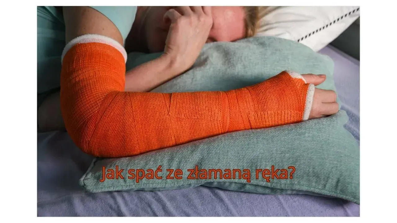 Osoba leży w łóżku z ręką w pomarańczowym gipsie. Tekst na poduszce pyta: "Jak spać z ręką w gipsie?".