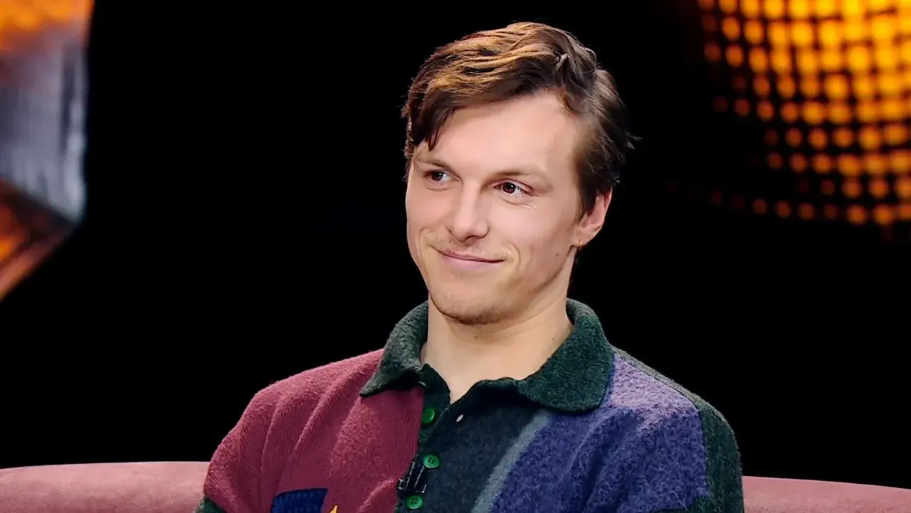 Uśmiechnięty Tomasz Włosok w kolorowym swetrze, jakby opowiadał o swoich najnowszych filmach.