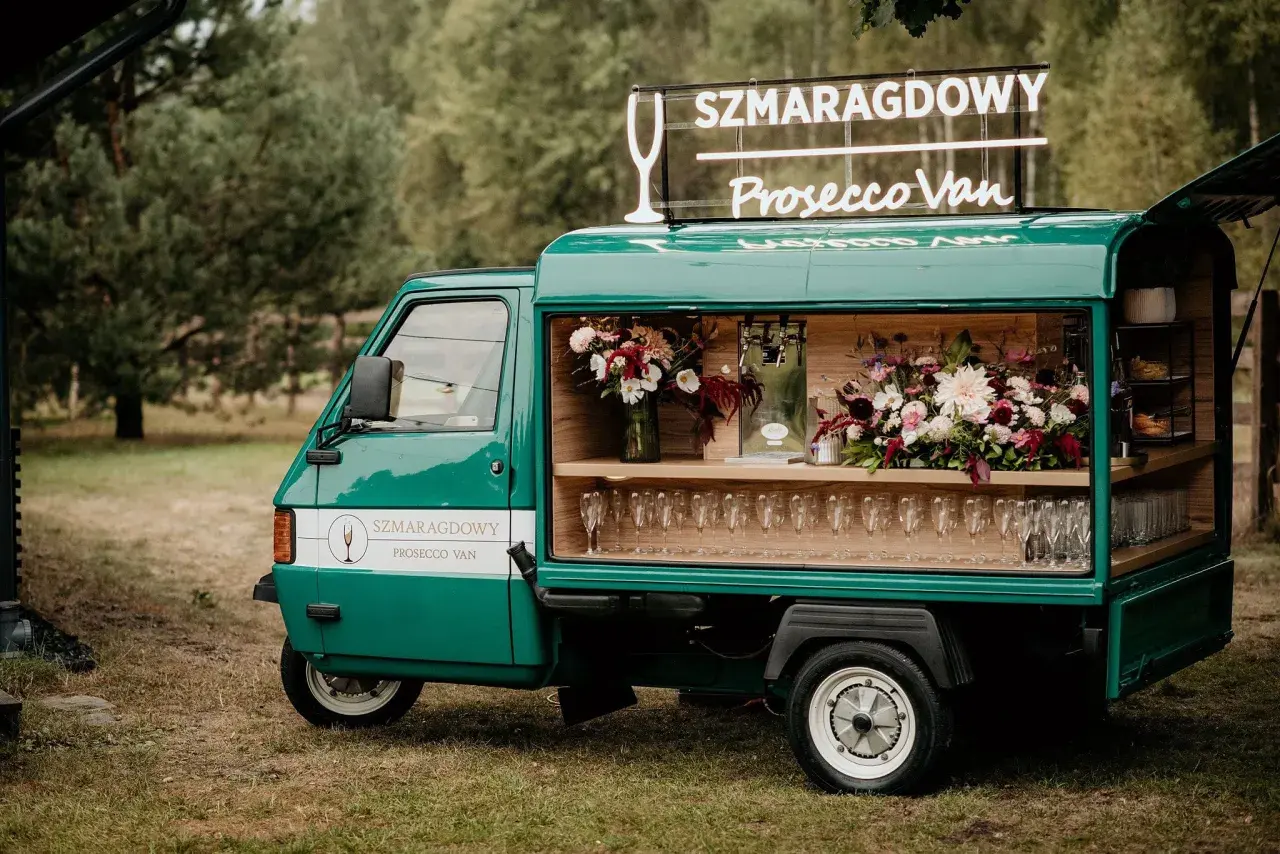 Zielony Prosecco Van "Szmaragdowy" z neonem i kwiatami, gotowy na przyjęcie.