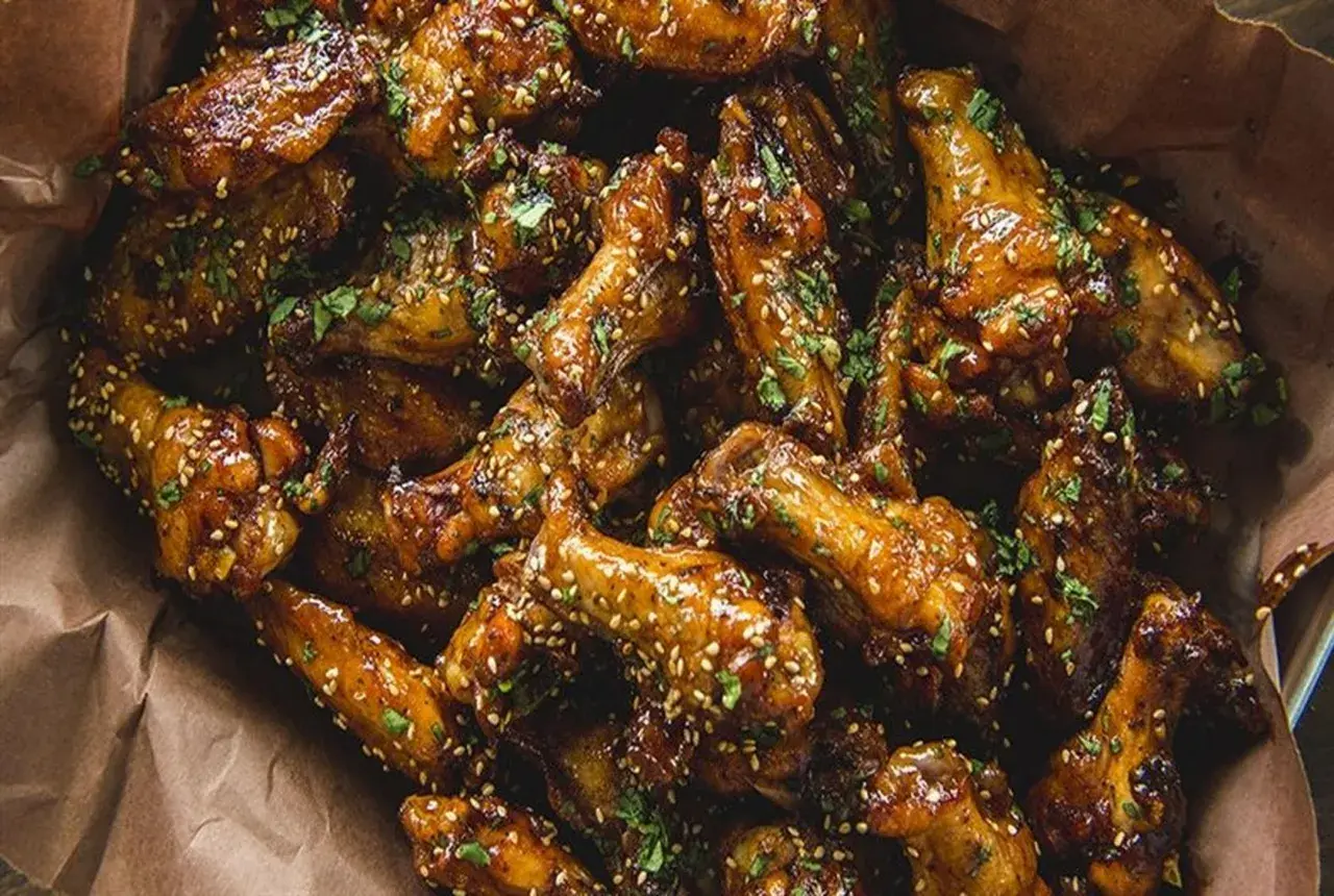 Ailes de poulet caramélisées, saupoudrées de sésame et de persil. Parfaites pour le temps de cuisson ailes de poulet sur bbq.