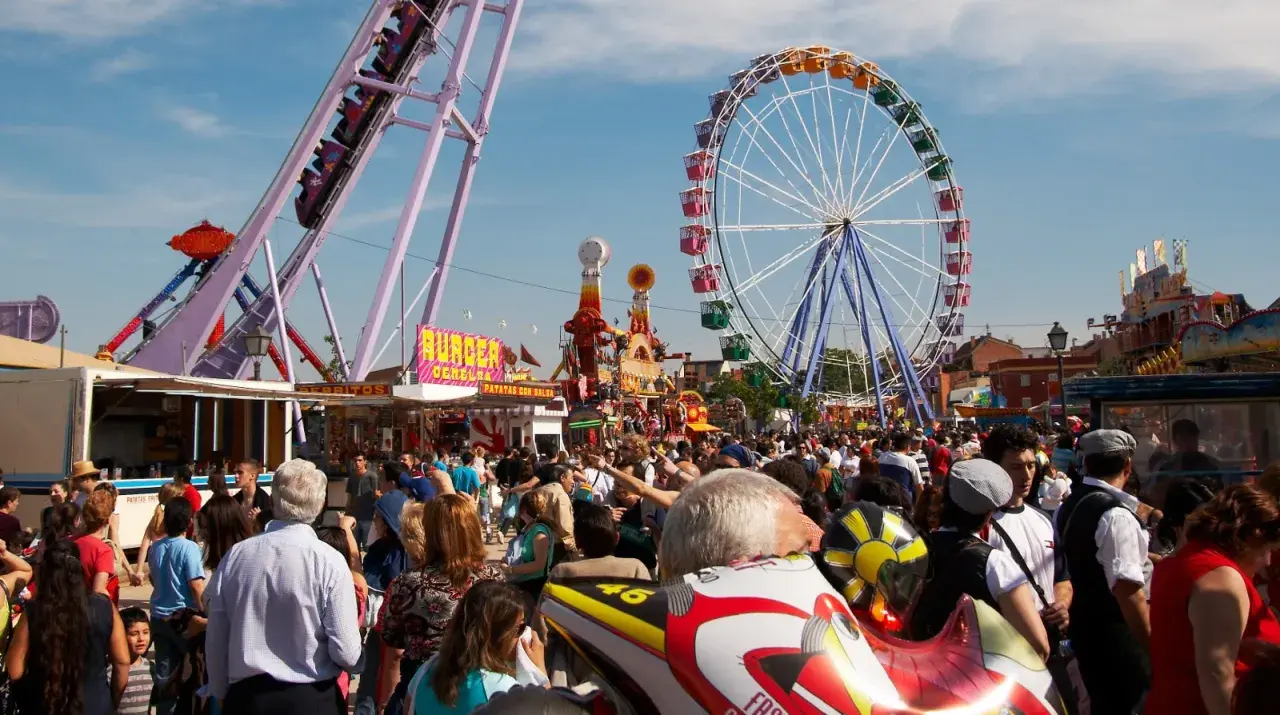 Feria en la Finca San Isidro Madrid con noria, atracciones y mucha gente disfrutando del día.