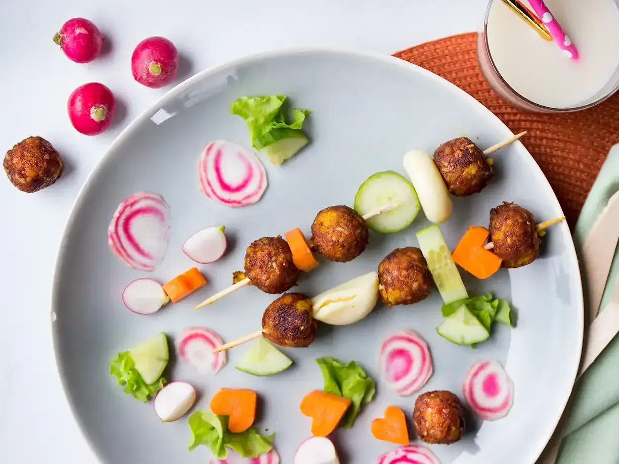 Vegetarisk mat för barn: Spett med vegetariska köttbullar, gurka, morötter och rädisor. En festlig och färgglad måltid.
