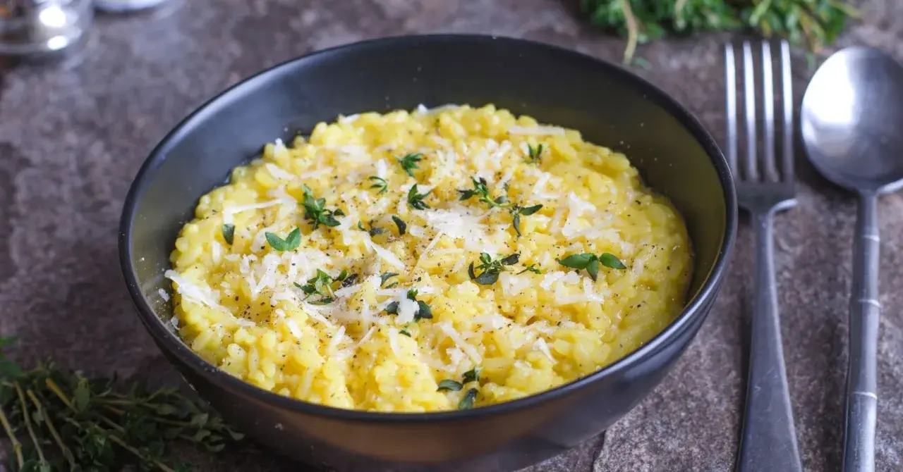 En krämig risotto alla milanese, toppad med riven parmesan och färska örter.