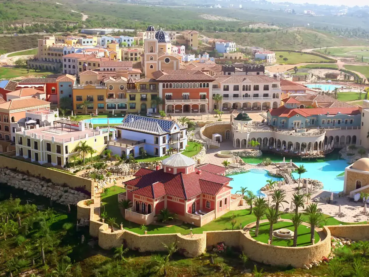 Vista aérea del hotel Villaitana en Benidorm, con sus coloridos edificios, piscinas y exuberante vegetación.