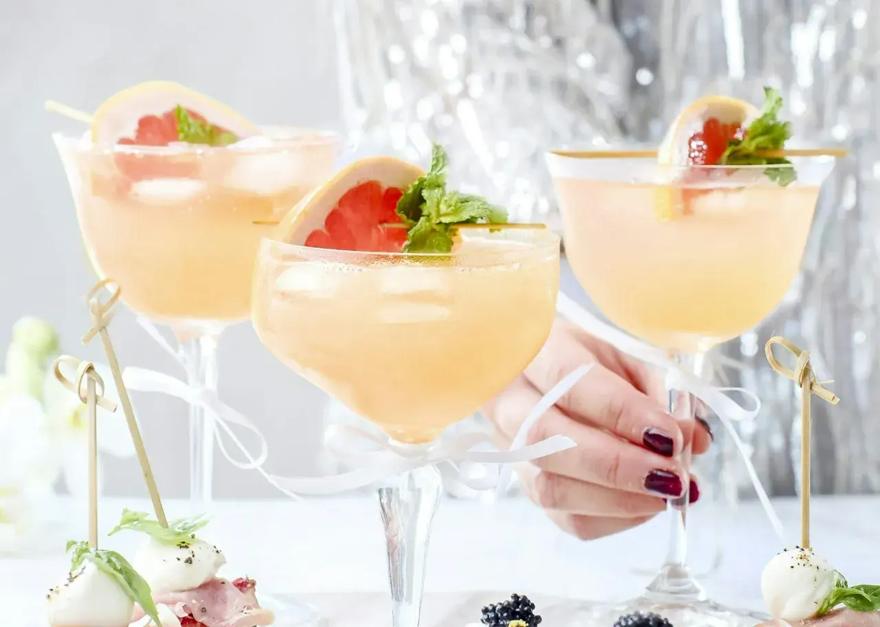 Tre eleganta glas med rosa drinkar, garnerade med grapefrukt och mynta. Perfekt drink till nyår!