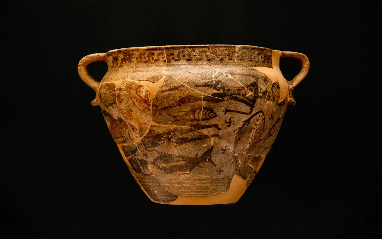 Antico vaso greco con decorazioni di pesci e figure, forse un'opera ispirata a **Giorgio Buchner**. Frammentato ma affascinante.