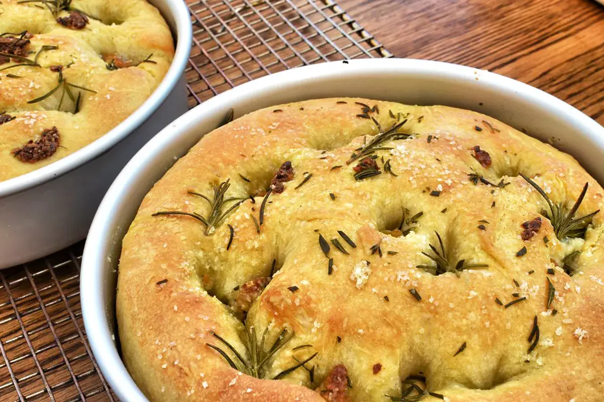 Focaccia senza glutine dorata, con rosmarino e sale grosso, appena sfornata e pronta per essere gustata.