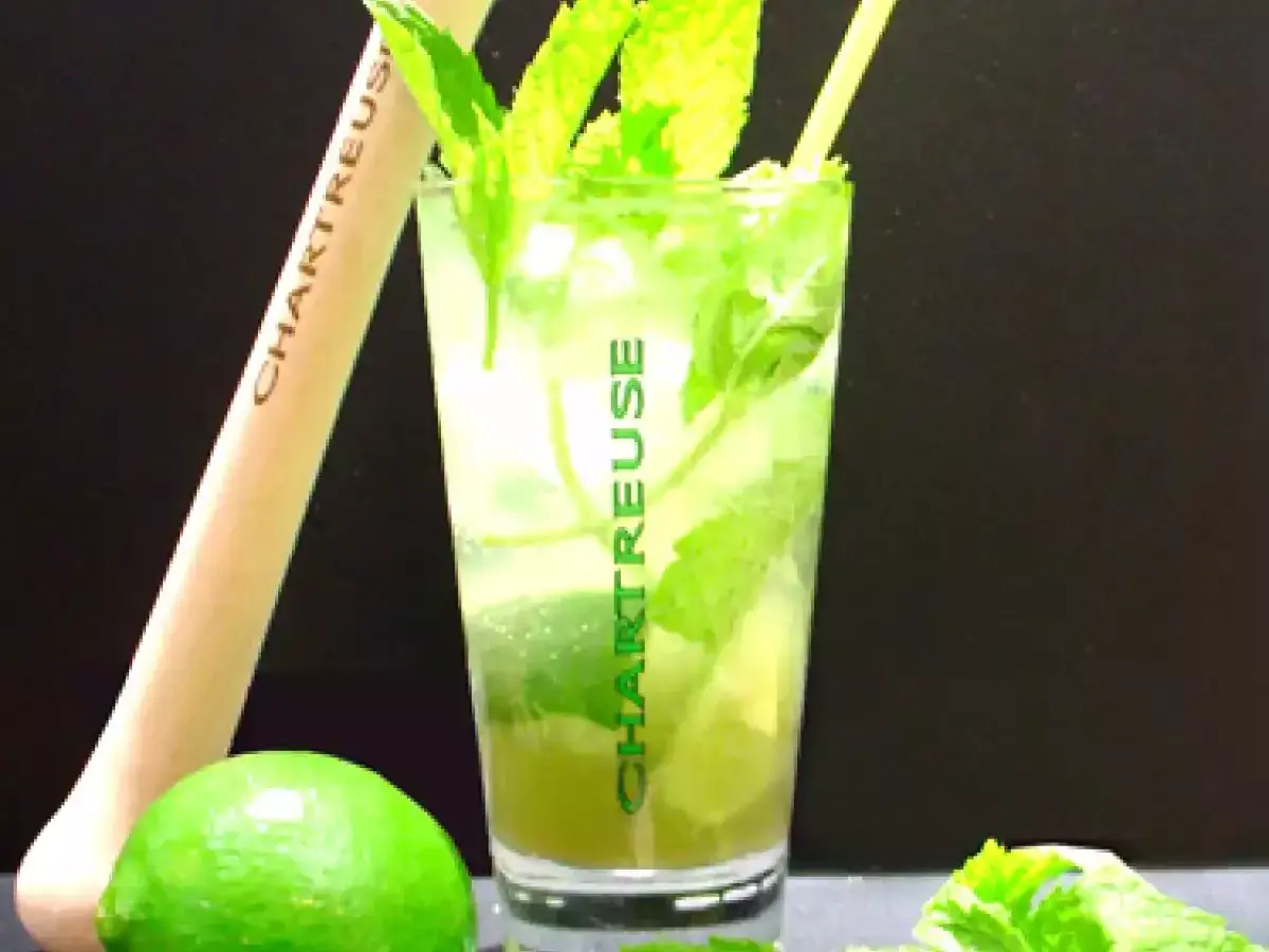 Un verre de cocktail Chartreuse, garni de menthe fraîche et de citron vert, prêt à être dégusté.