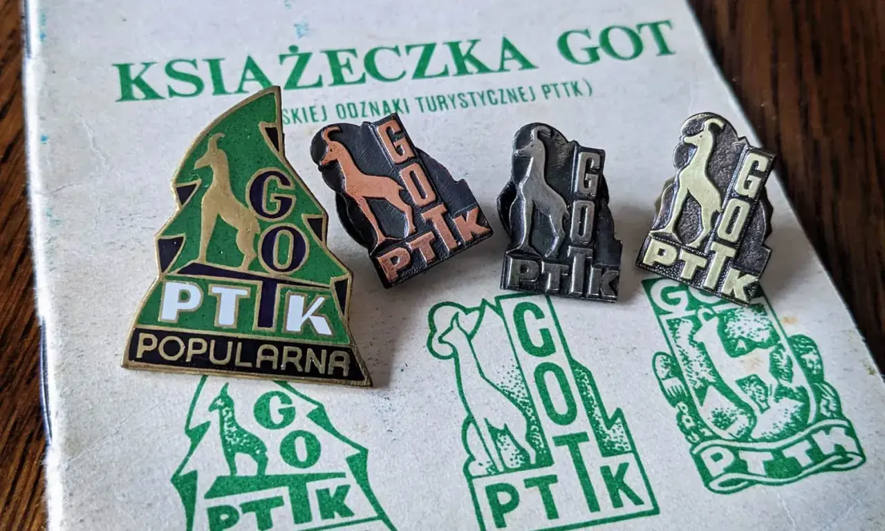 Książeczka GOT z odznakami turystycznymi PTTK. Widoczne cztery odznaki z kozicą i napisem GOT PTTK w różnych kolorach.