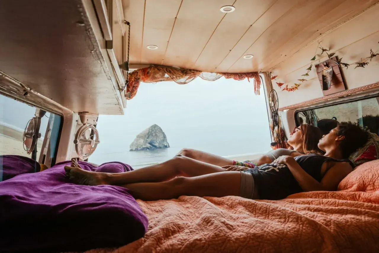 Deux amies profitent d'une vue imprenable sur la mer depuis leur spot van en Normandie.