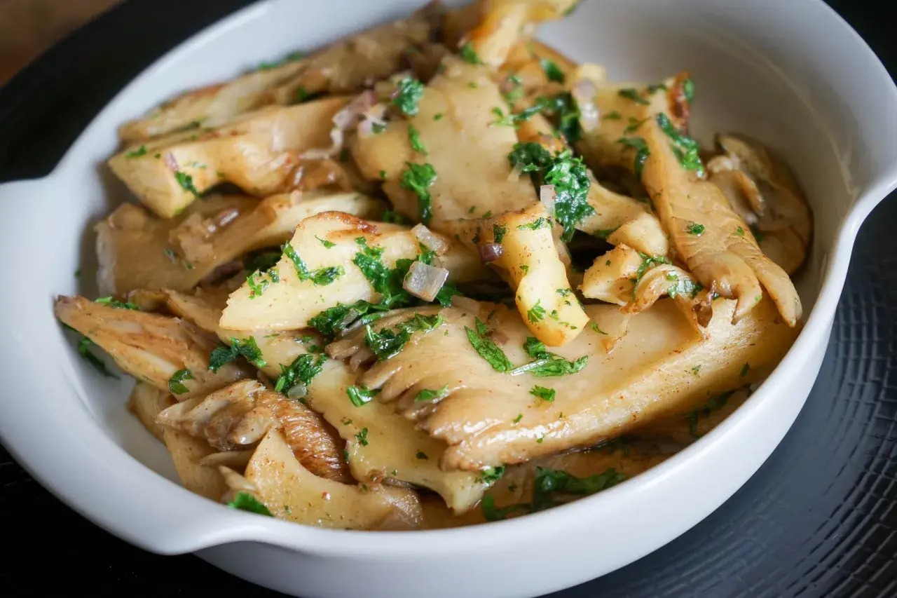 Délicieuse pleurote recette, des champignons sautés aux herbes fraîches dans un plat blanc.