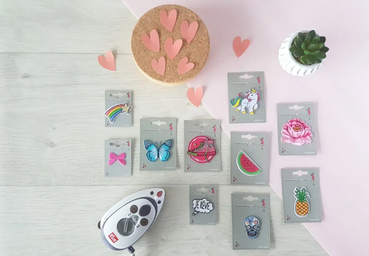Un fer à repasser et divers patchs thermocollants : étoile filante, papillon, basket, pastèque, licorne, fleur, ananas, crâne, et bulle "Je rêve". Idéal pour créer un patch thermocollant personnalisé.