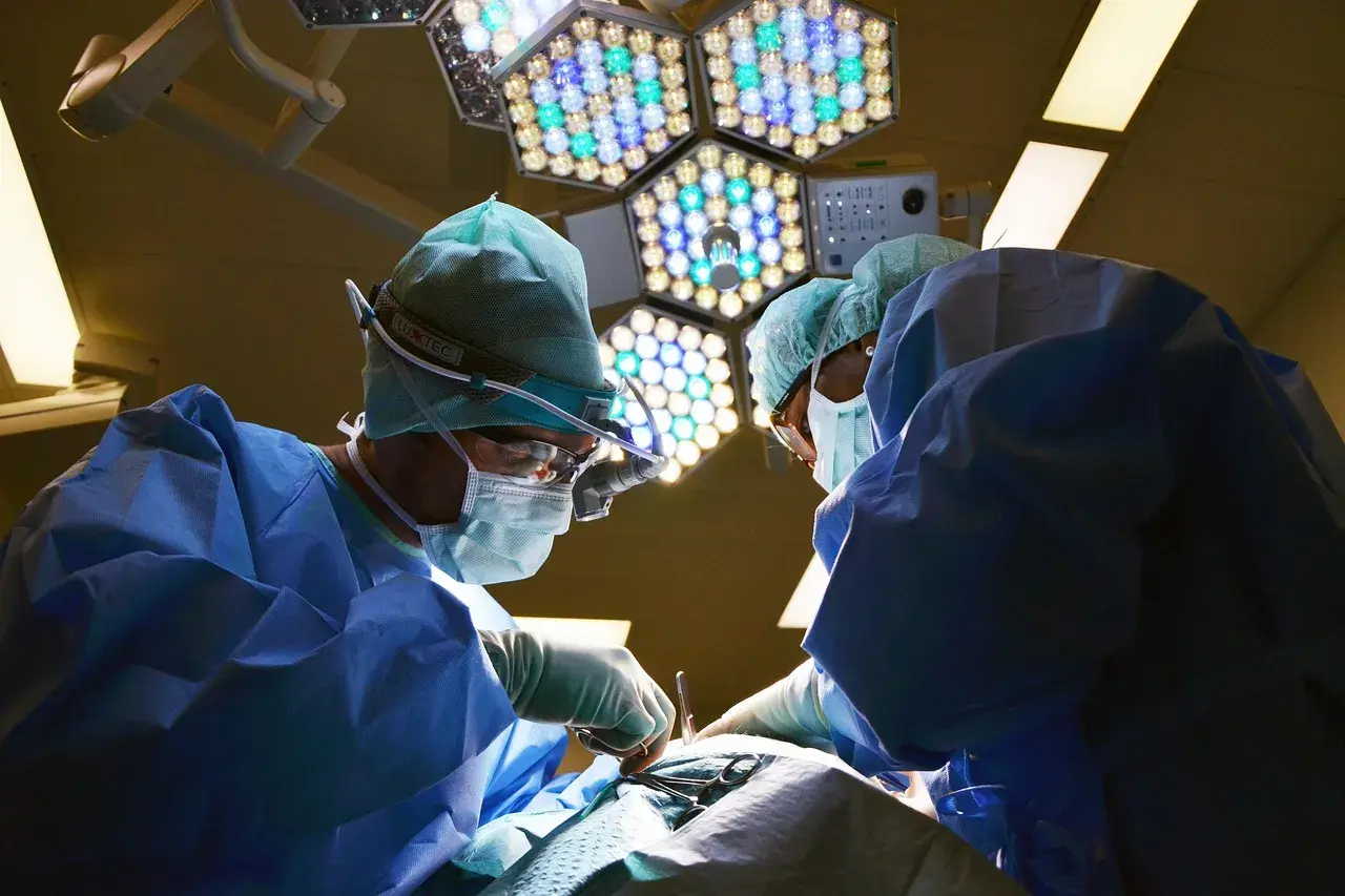 Chirurdzy w sterylnych strojach pracują pod jasnym światłem lampy operacyjnej. Po zabiegu mogą wystąpić narkoza skutki uboczne.