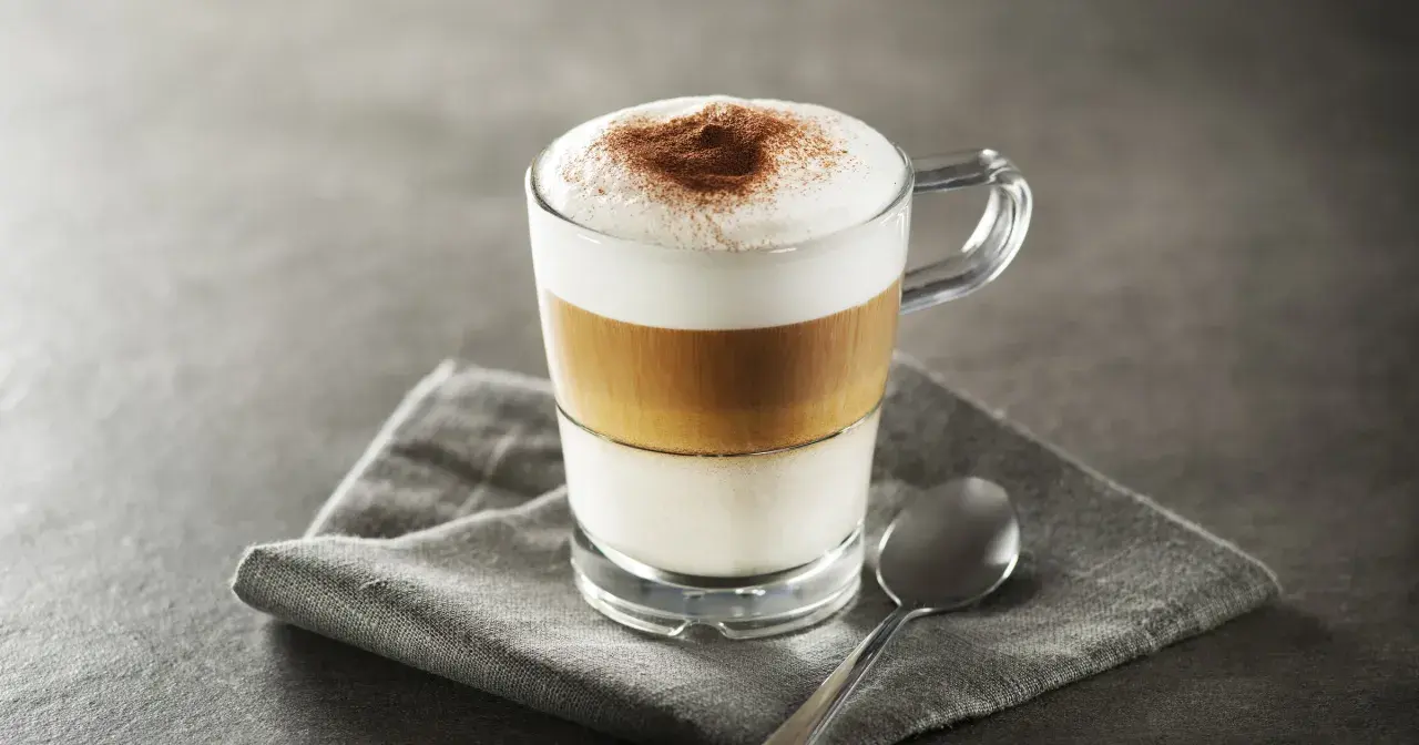 Idealne latte macchiato proporcje: mleko, espresso i pianka tworzą apetyczne warstwy. Posypane kakao.