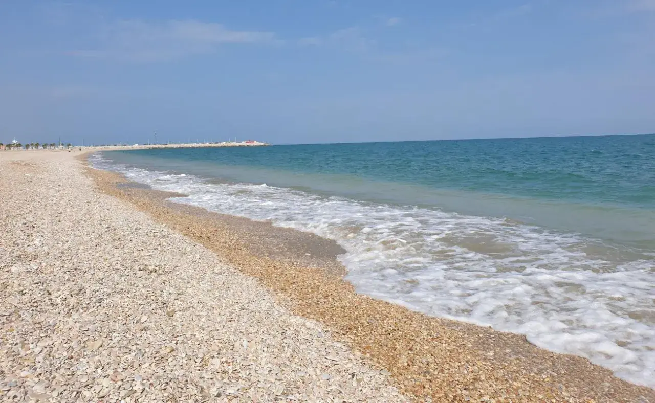 Spiaggia di ciottoli a Civitanova Marche, con il mare azzurro e le onde che lambiscono la riva.